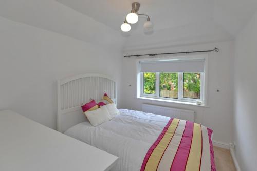 a white bedroom with two beds and a window at Finest Retreats - DeBarnes House in Solihull