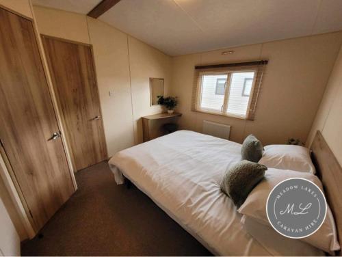 a bedroom with a bed with white sheets and a window at The Meadows 34 - Golden Palm Resort, pet friendly, WiFi & bed linen - Meadow Lakes Caravan & Lodge Hire in Chapel Saint Leonards