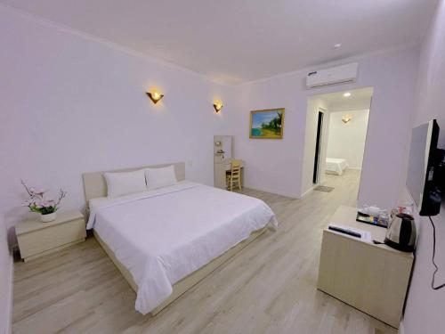 - une chambre blanche avec un lit blanc et une télévision dans l'établissement Sài Gòn - Hà Tiên, à Hà Tiên