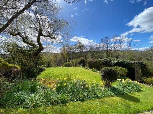 um jardim com um relvado com flores e uma árvore em Sandholme Cottage - Pateley Bridge em Pateley Bridge