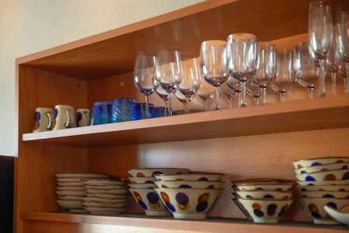 a shelf with wine glasses and plates and bowls at フェリスヴィラスイート伊良部島・長浜ベイ in Miyako Island