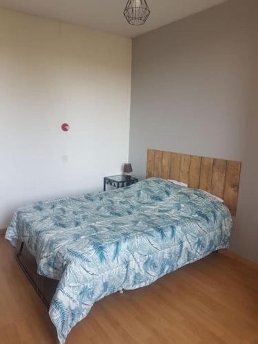 Schlafzimmer mit einem Bett mit blauer Decke in der Unterkunft Maison 3 chambres in La Frugerie