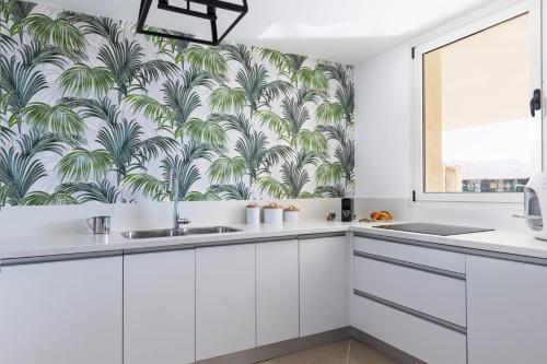 una cocina con armarios blancos y papel pintado tropical en YalaRent Golf Residence 3BR apt in luxury complex with pool, en Eilat