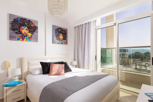a bedroom with a bed and a large window at YalaRent Golf Residence 3BR apt in luxury complex with pool in Eilat