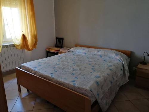 a bedroom with a bed with a blue comforter and a window at Albisola, a 50 m dal mare in Albisola Superiore