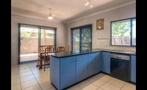 a kitchen with blue cabinets and a table and chairs at the Ningaloo breeze villa 2/10 in Exmouth