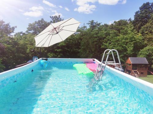 a swimming pool with an umbrella and a swimming pool at Chata Hrabovská 