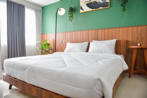 - une chambre avec un grand lit blanc et un mur bleu dans l'établissement Stay G Service Residence Sentul, à Kedungmanggu