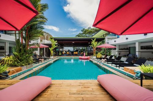 een zwembad in een hotel met rode parasols bij CC's Hideaway Kata - SHA Plus in Kata Beach
