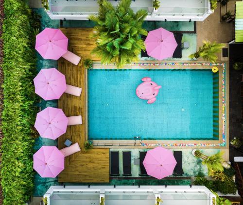 an overhead view of a swimming pool with pink umbrellas at CC's Hideaway Kata - SHA Plus in Kata Beach