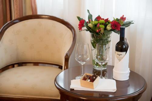 a table with a bottle of wine and a vase of flowers at Landhotel Zum Hessenpark in Neu-Anspach