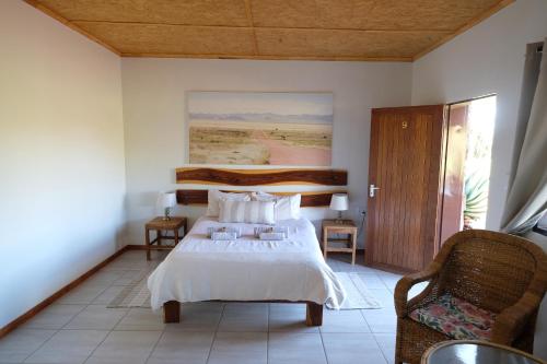 a bedroom with a bed and a chair at Duwisib Guest Farm in Duwisib