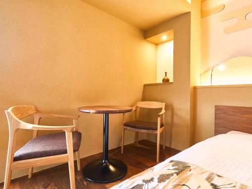 a room with two chairs and a table and a bed at 枳殻の杜 Kikoku no mori in Kyoto