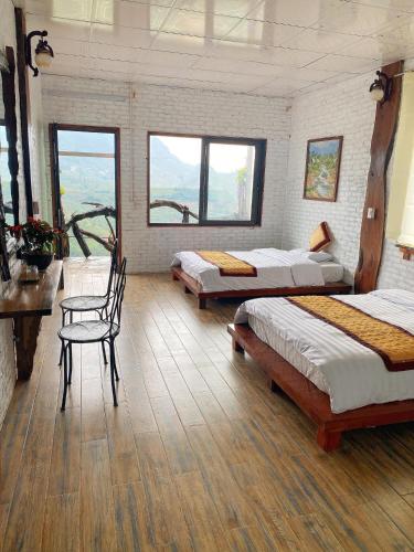 a room with three beds and a table and chairs at Hà Lù Homestay in Lao Cai