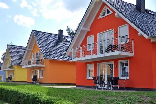 ein rotes und gelbes Haus mit Stühlen davor in der Unterkunft Ferienwohnungen Appartements - Ferienhaus Müritzwelle in Marienfelde