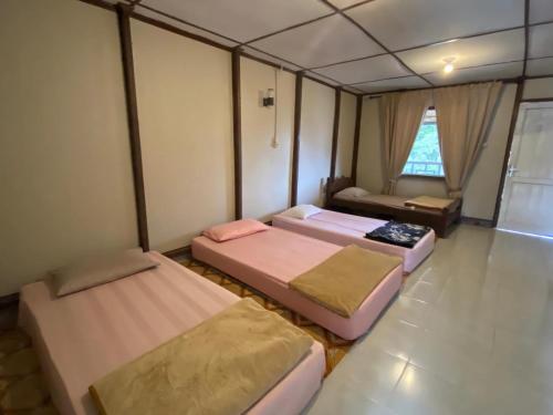 una camera con due letti in una stanza con finestra di RON'S Guest House Berastagi Backpacker Rooms a Berastagi