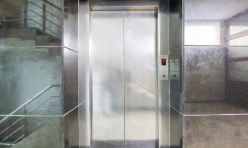 a metal elevator in a room with a staircase at Treebo Trinetar International in Jammu
