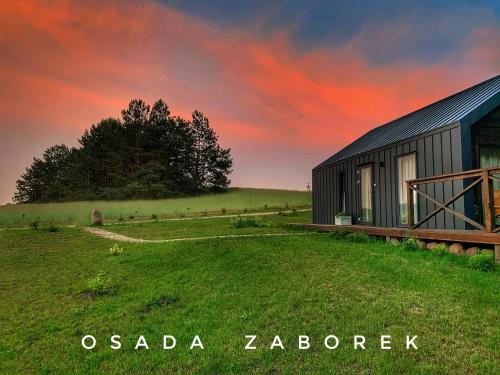 een schuur in een veld met een rode hemel bij Osada Zaborek in Janów Podlaski