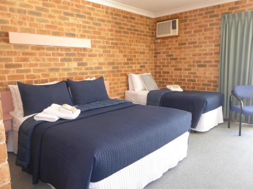 a bedroom with two beds and a brick wall at The Lydoun Motel in Chiltern
