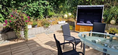 a patio with a glass table and chairs and flowers at Am alten Siel in Wilhelmshaven
