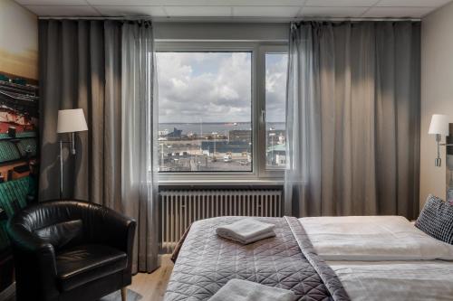 a bedroom with a bed and a chair and a large window at Dream - Luxury Hostel in Helsingborg