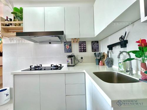 a white kitchen with a sink and a stove at Melaka Novo 8 Residence - Jonker Street by Stayrene in Melaka