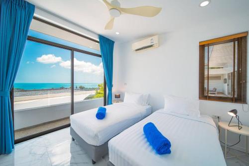 two beds in a room with a view of the ocean at Nastha Villa 3 bedrooms in Koh Samui 