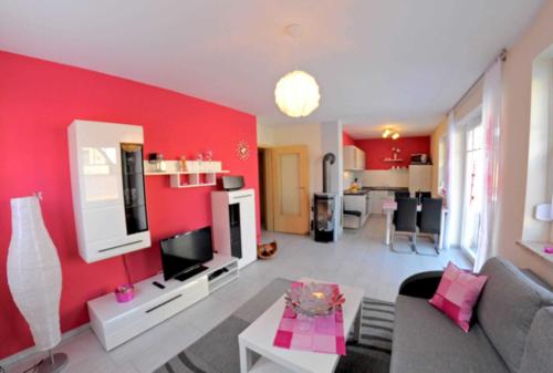 sala de estar con pared de acento rojo en Ferienwohnungen Appartements - Ferienhaus Müritzlust, en Marienfelde