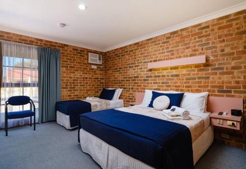 a bedroom with two beds and a brick wall at The Lydoun Motel in Chiltern