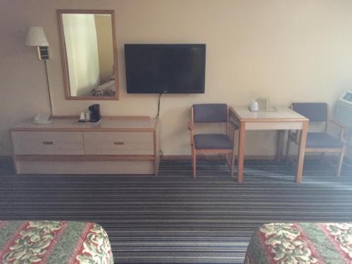 a hotel room with a desk and a tv and a table at Budget Inn - Cambridge in Fairdale