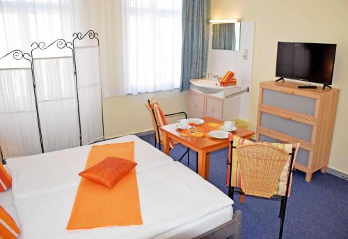 a room with a dining table and a room with a television at Appartementhaus Sellin in Ostseebad Sellin