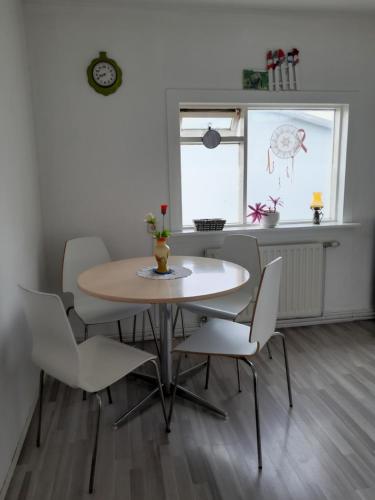 a dining room with a table and white chairs at Kyrrðarstaður in Selfoss
