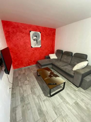 a living room with a couch and a red wall at appartement de charme proche de Moissac in Labastide-du-Temple