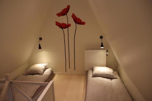 Dos camas en una habitación con dos flores rojas en la pared en Skelgaard Ferielejlighed en Jelling