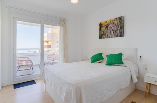 Habitación blanca con cama y balcón. en Apartamento frente al mar TORRES DE PLAYAMAR en Torremolinos