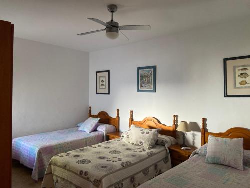 Fernán PérezにあるCasa Rural El Jazmineroのベッドルーム1室(ベッド2台、シーリングファン付)