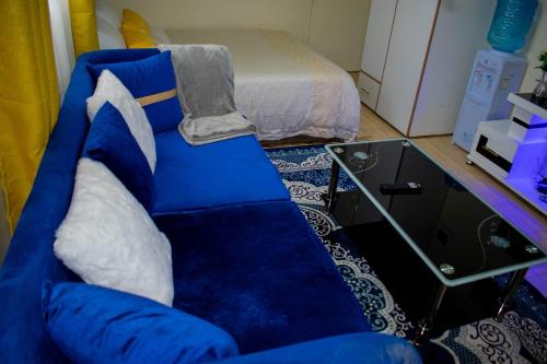 a blue couch in a living room with a bed at BELEEN HOMES in Limuru