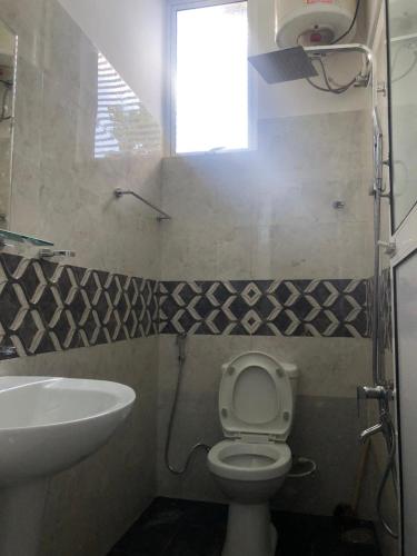 a bathroom with a toilet and a sink and a window at Randi Apartments B&B in Boralesgamuwa