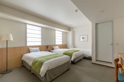 two beds in a room with two windows at Shin-Osaka Station Hotel in Osaka