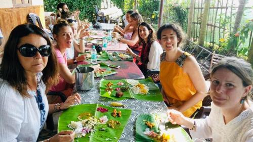 Un gruppo di donne sedute a tavola che mangiano cibo di Dream Nest Guest House a Alleppey