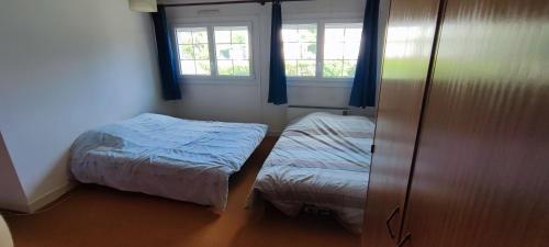 1 dormitorio pequeño con 2 camas y 2 ventanas en Maison d'hôtes chez Thibaut, en Pougues-les-Eaux