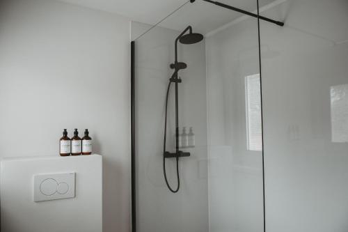 La salle de bains est pourvue d'une douche avec une porte en verre. dans l'établissement Maas Suites - The River House, Maastricht - Lanaken, à Lanaken