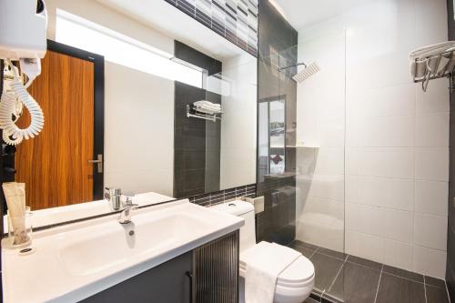 a bathroom with a sink and a toilet and a mirror at Flemington Hotel in Taiping