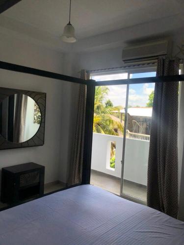 a bedroom with a bed and a view of a balcony at Randi Apartments B&B in Boralesgamuwa