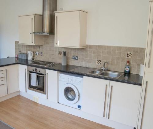 a kitchen with a washing machine and a sink at Thornhill Apartment in Sunderland