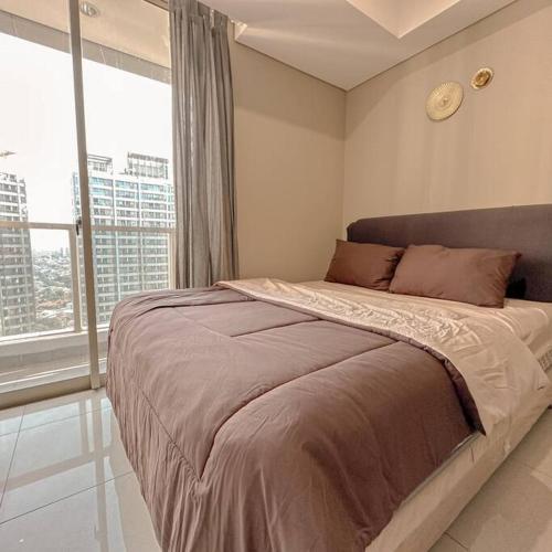 a bedroom with a large bed and a large window at Studio, West Jakarta Oasis, Netflix, Pool, Mall in Jakarta