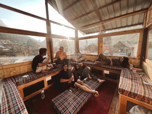 a group of people sitting in a room with windows at Mitra Hostel Sonamarg in Sonāmarg