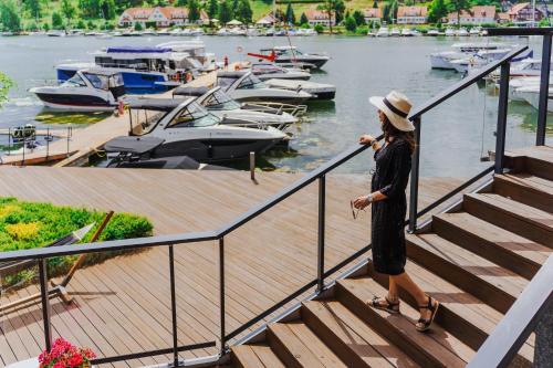 a woman standing on stairs near a marina with boats at Hotel Mikołajki Leisure & SPA - Destigo Hotels in Mikołajki