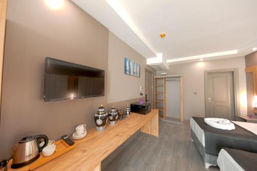 een woonkamer met een bed en een flatscreen-tv bij İstanbul City Airport Hotel in Arnavutköy