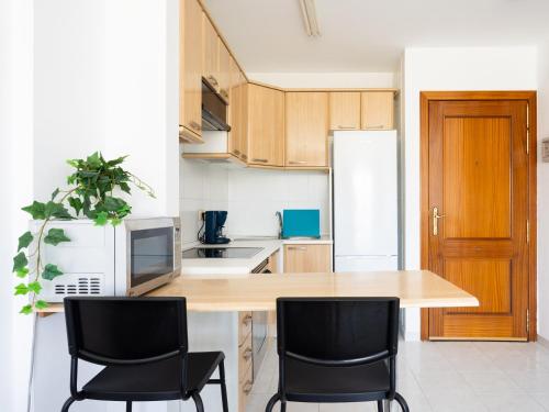 a kitchen with a wooden table and two black chairs at Live Medano Mirazul in El Médano